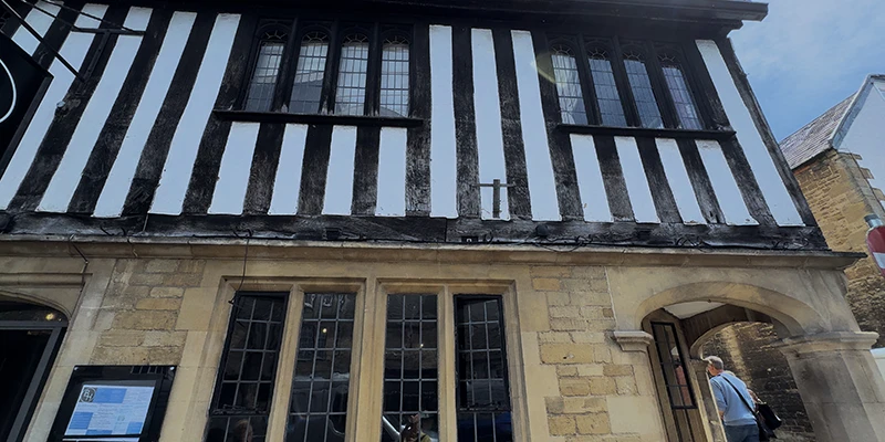 Distinctive black-and-white striped half-timbered Tudor building with stone arched entrance