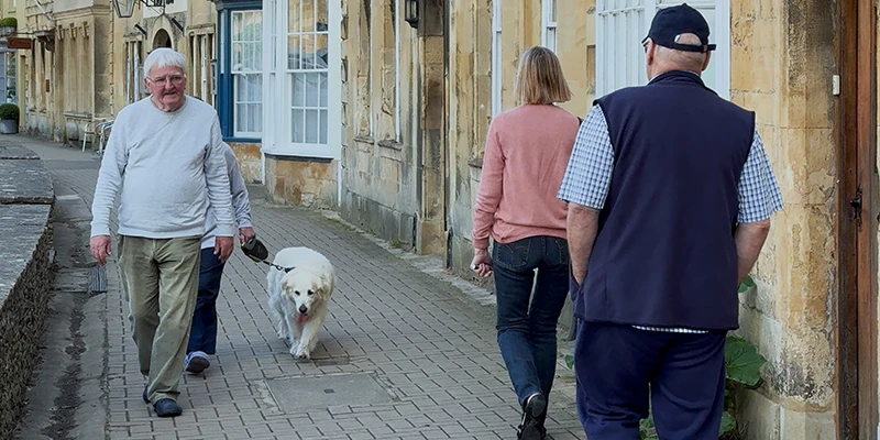 Visitors strolling with a dog along the main lane in Chipping Campden