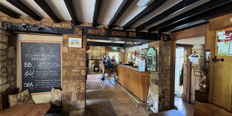 Pub interior showing low timber-beam ceiling, bar, and Donnington chalkboard