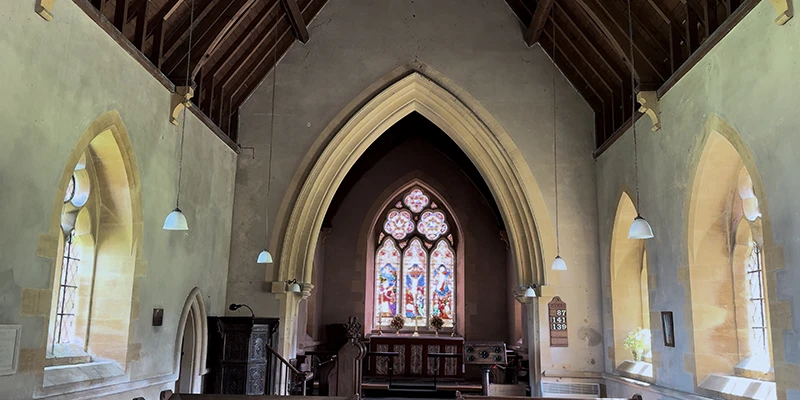 Interior of St Barnabas showing nave, pews and stained-glass altar window
