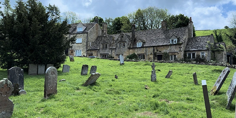 Churchyard with weathered headstones and stone cottages behind