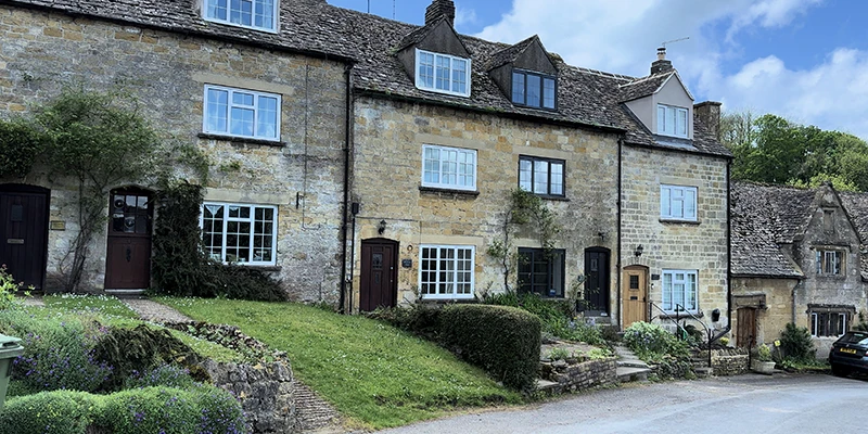 Row of stone cottages on the green with dormer windows and stone-tiled roofs