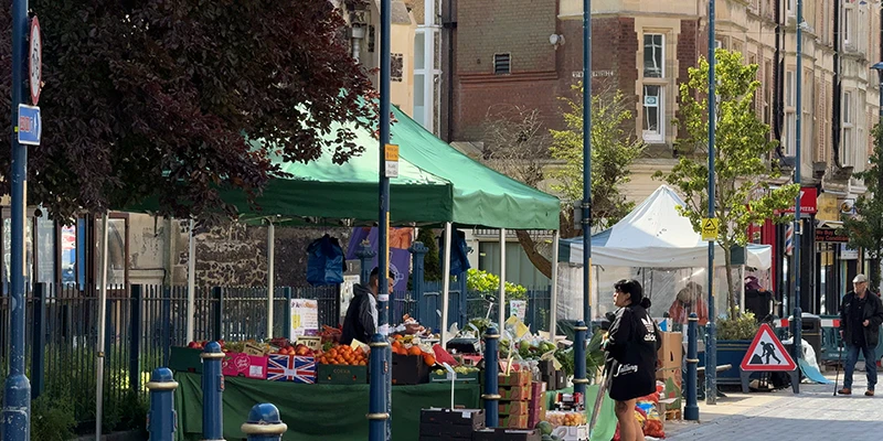 Outdoor market stalls under green canopies in Dover