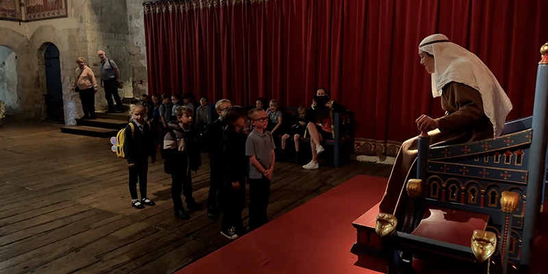 A guide in period costume addressing students in the King's Hall at Dover Castle