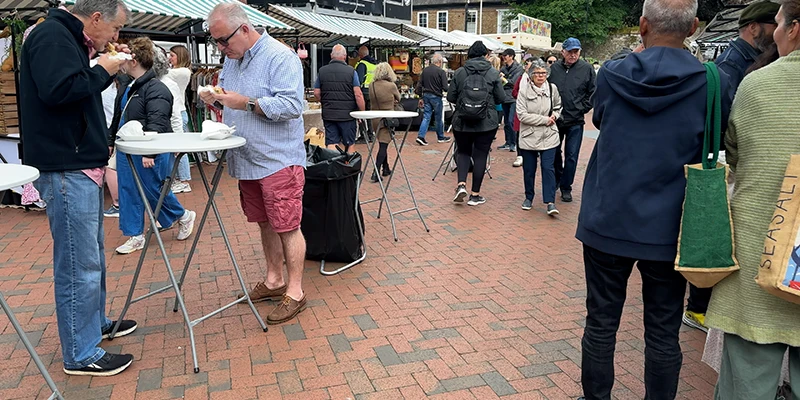 Shoppers eating at stand-up tables in Ely Market Place