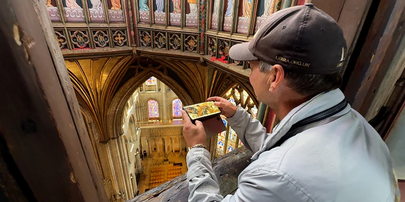 A visitor photographing the painted ceiling reflected in a mirror at Ely Cathedral