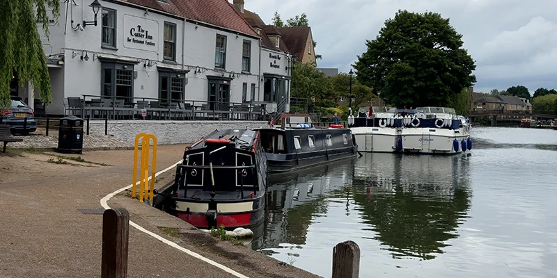 Narrowboats moored at Ely Marina on the Great Ouse with a riverside pub behind
