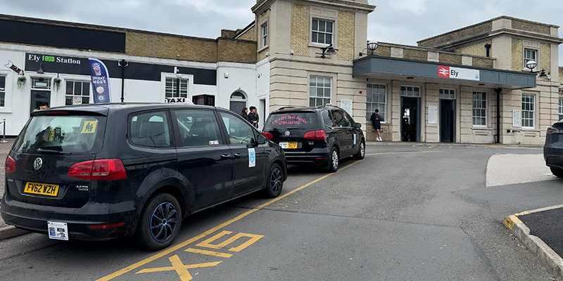 The exterior of Ely railway station with the taxi stand out front