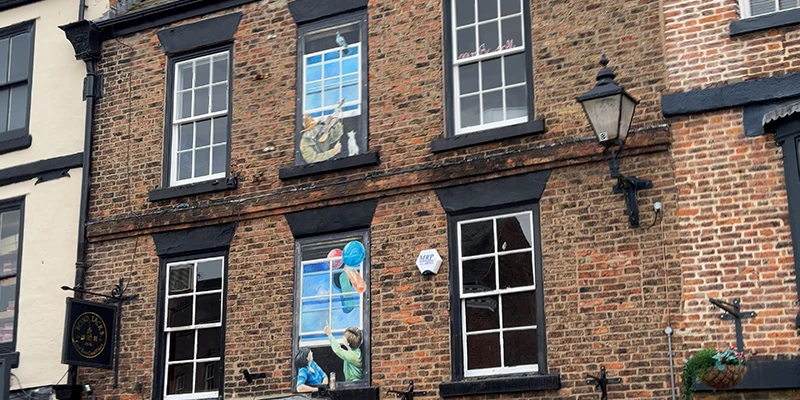 Painted and real windows side by side on a brick facade in Knaresborough