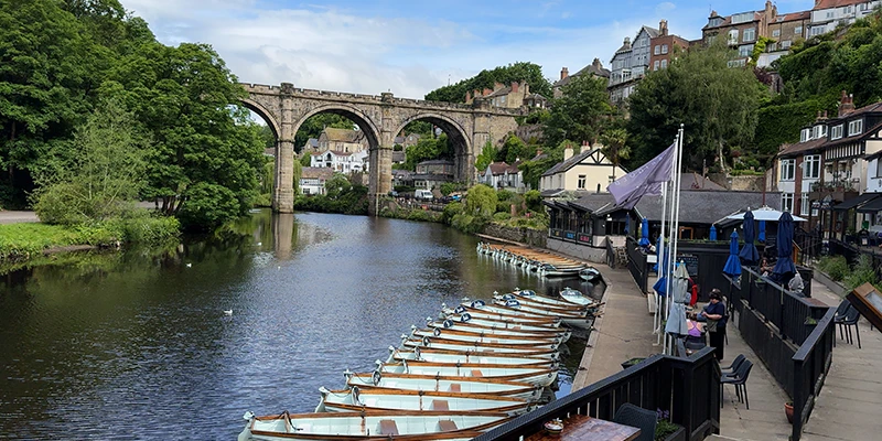 The riverside walkway at Knaresborough with rowing boats moored below the viaduct