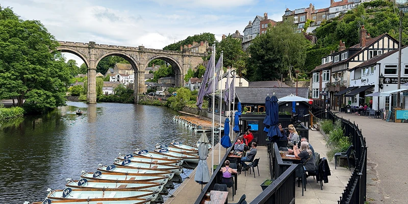 Rowing boats lined along the riverside at Knaresborough beneath the viaduct