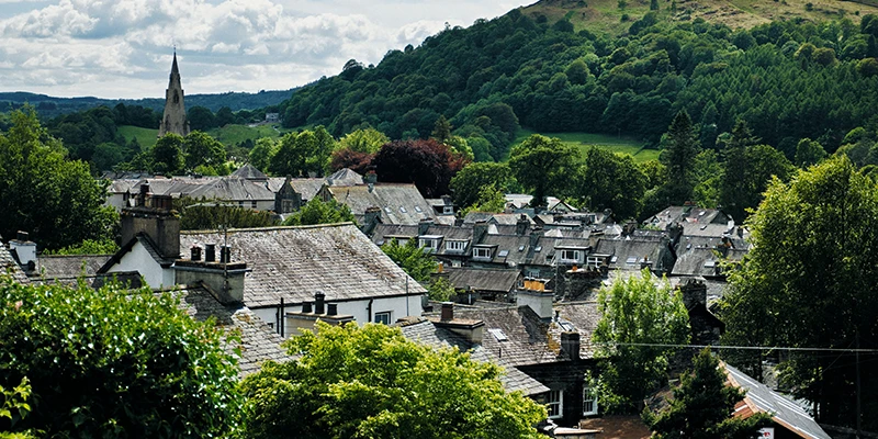 Slate rooftops of Ambleside seen from above with the church spire and fells behind