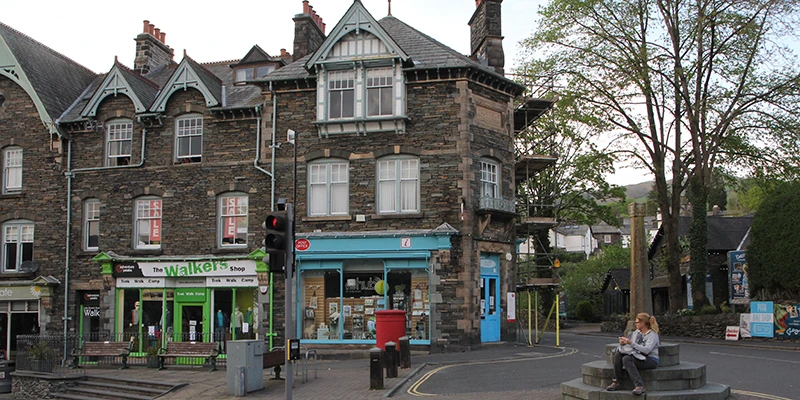 A street corner in Ambleside with painted shopfronts and trees