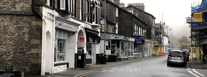 Stone-fronted buildings and shops lining a street in central Windermere