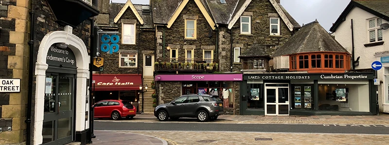Oak Street sign on a stone archway with shops and cottages beyond
