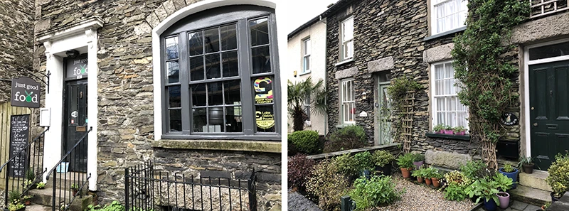 Stone cottage with a large bay window and garden behind iron railings