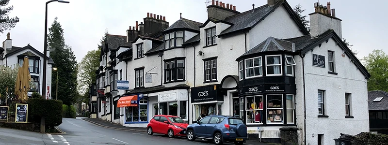Row of white painted buildings and parked cars on a Windermere street