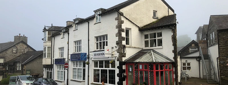 White buildings with red timber trim on a foggy Windermere street