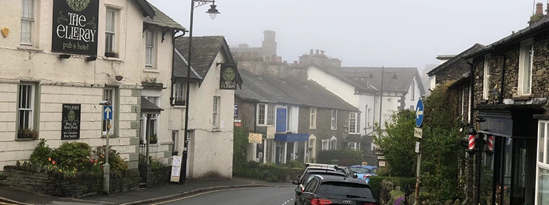 Pub and stone houses along a misty street in Windermere
