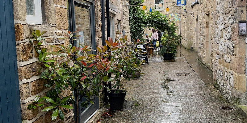 A narrow flower-lined alley between stone buildings in Bakewell