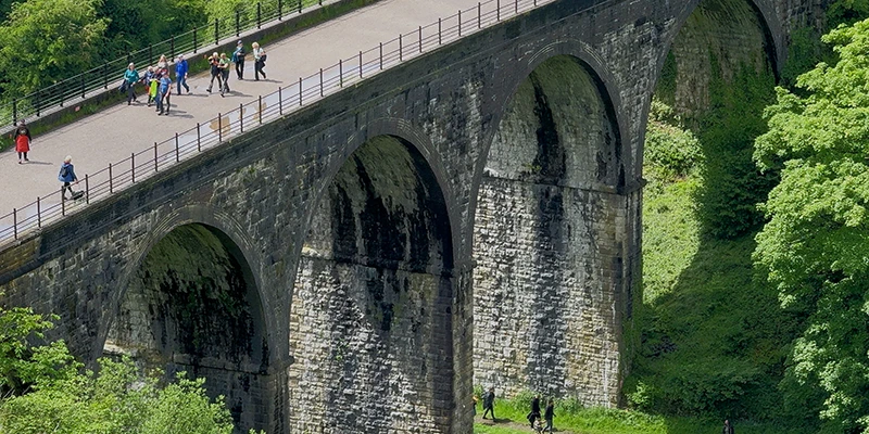 Walkers crossing the top of the old viaduct near Castleton
