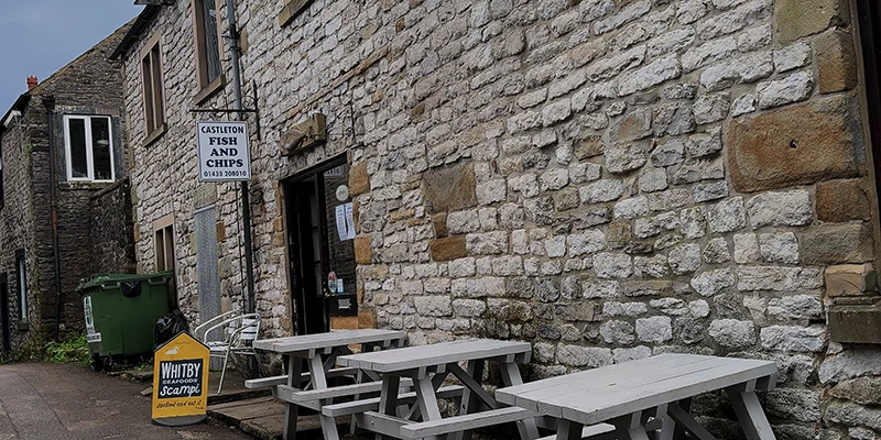A village pub with outdoor tables serving fish and chips in Castleton