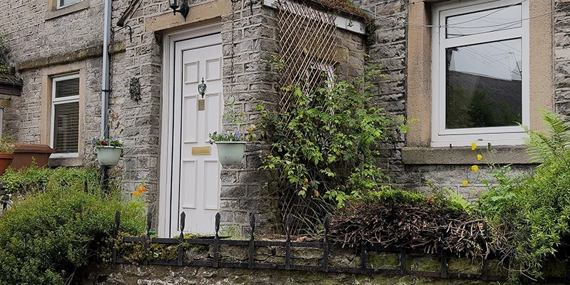 A traditional stone cottage with a white door in Castleton
