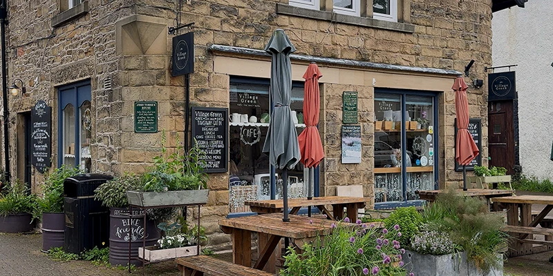 A village pub with red umbrellas and outdoor seating in Eyam