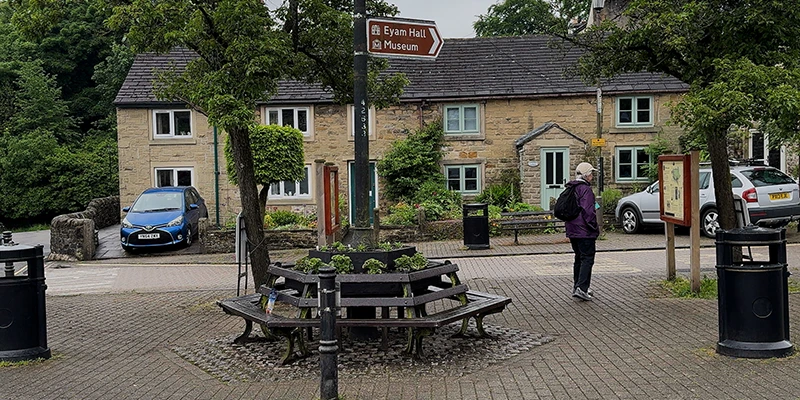 The village square of Eyam with a bench and signpost