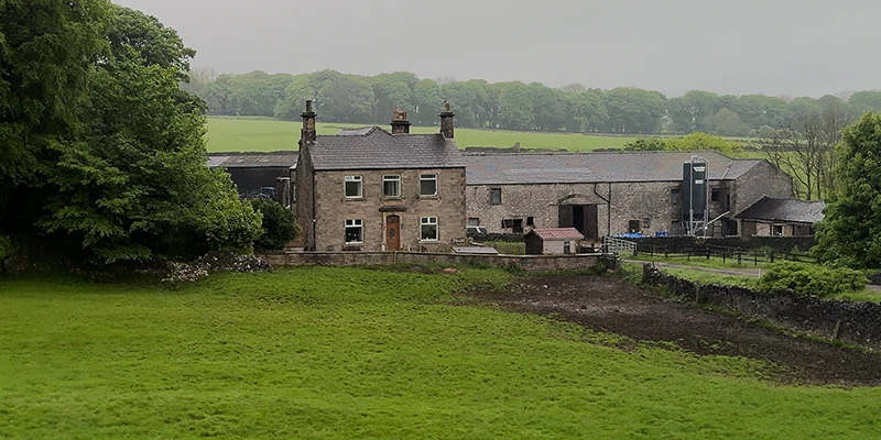 A stone farmhouse in the green fields around Eyam