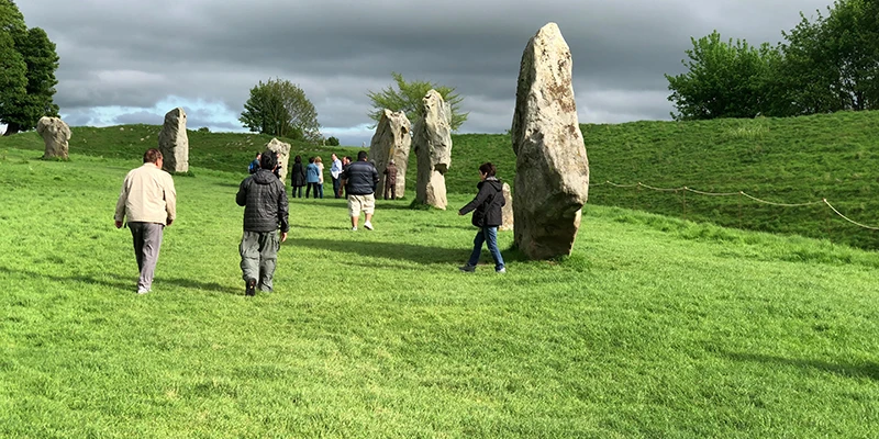 Two visitors standing beside a massive stone at Avebury