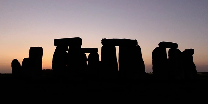 The stones of Stonehenge dark against a colored sunset sky