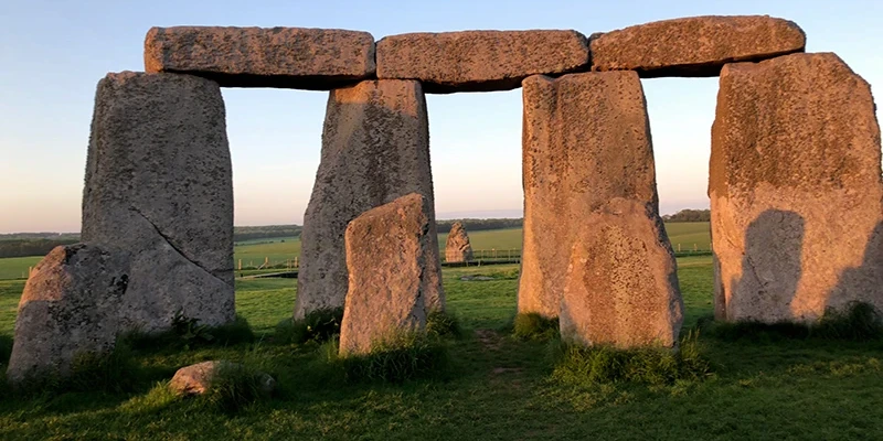 A visitor standing beside the sarsen stones at Stonehenge