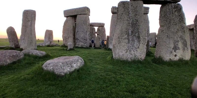 Stonehenge seen from the visitor path with the green downland around it