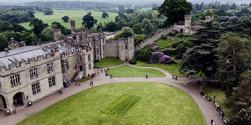 The wide grass courtyard of Warwick Castle enclosed by the curtain wall