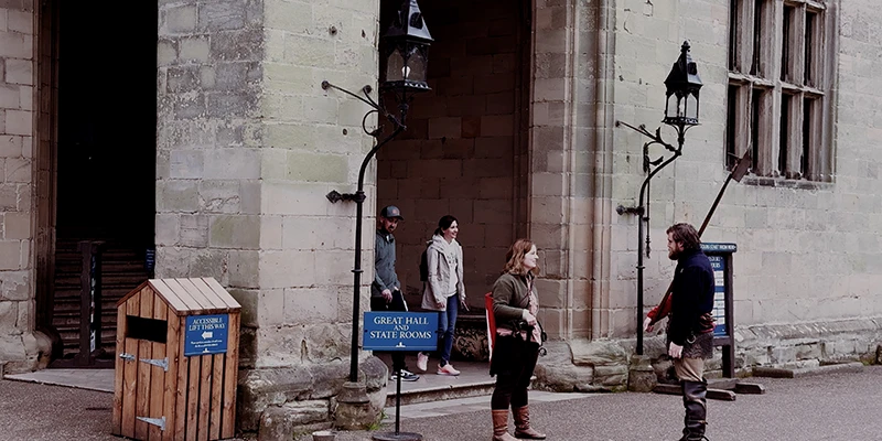 Costumed guide in medieval dress in the courtyard of Warwick Castle