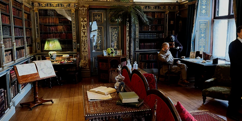The library at Warwick Castle, books floor to ceiling with a window onto the grounds