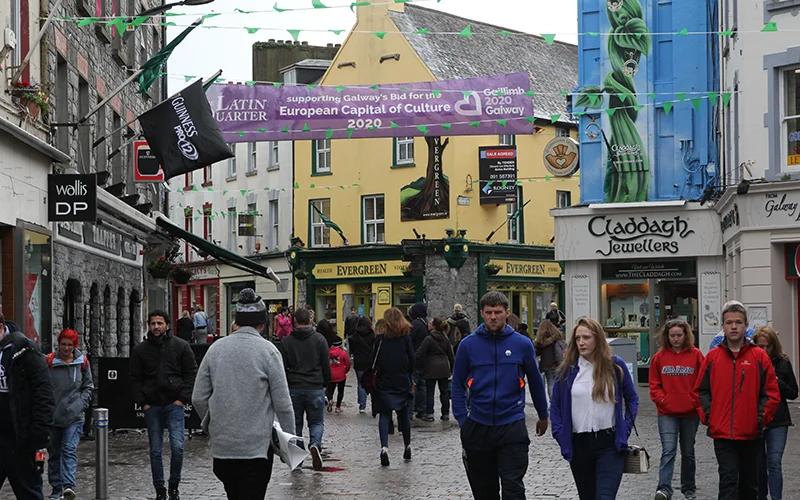 Crowded pedestrian street in Galway with colorful shopfronts