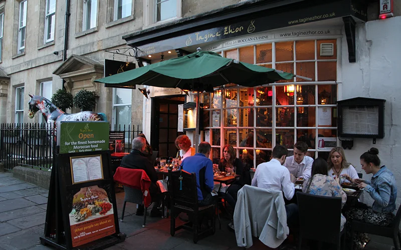 People eating at outdoor tables outside a pub in Bath