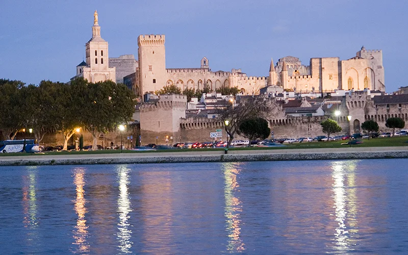 The Papal Palace at Avignon lit at dusk and reflected in the river