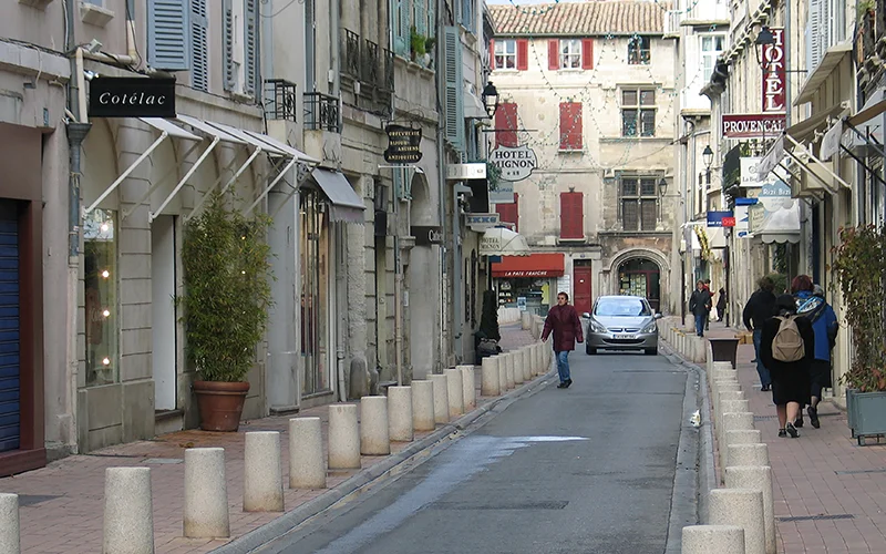 Narrow street in Avignon with shops and shuttered houses