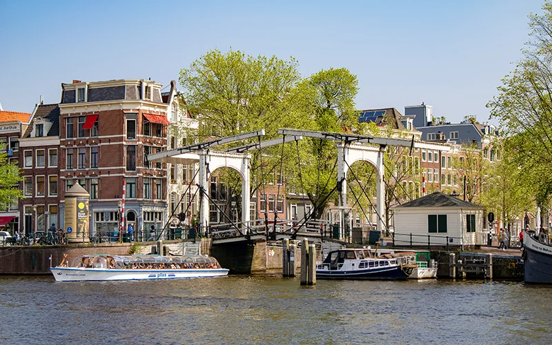Canal in Amsterdam with a wooden drawbridge and tour boat