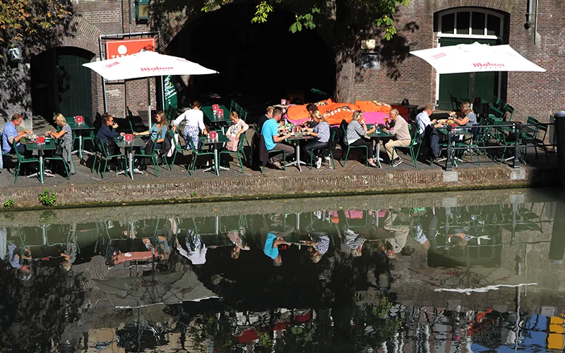 Waterside cafe tables beneath a brick arch in Utrecht