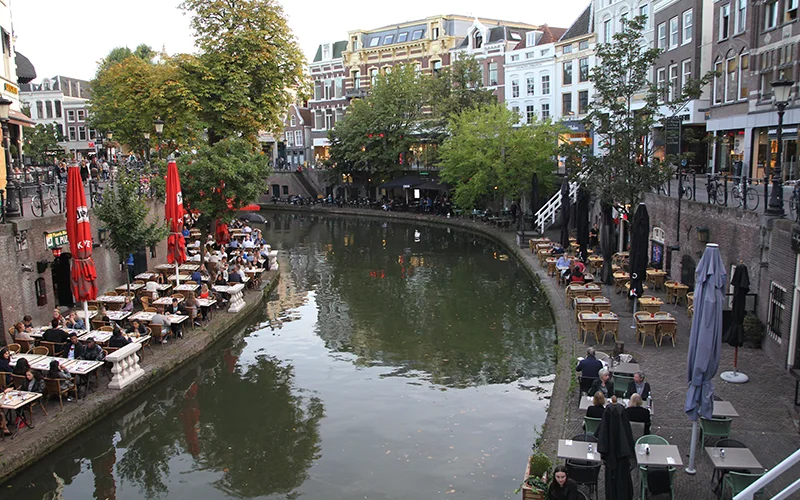 Canal in Utrecht with red cafe umbrellas along the wharf
