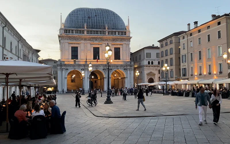 The Piazza della Loggia in Brescia at dusk with cafe tables