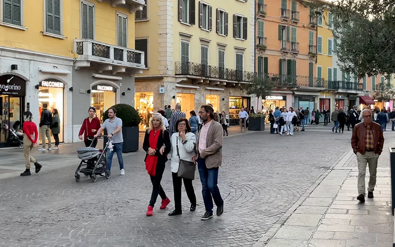 Shopping street in Brescia with pedestrians and lit shopfronts