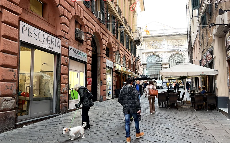 Narrow street in the old town of Genoa with a fish shop