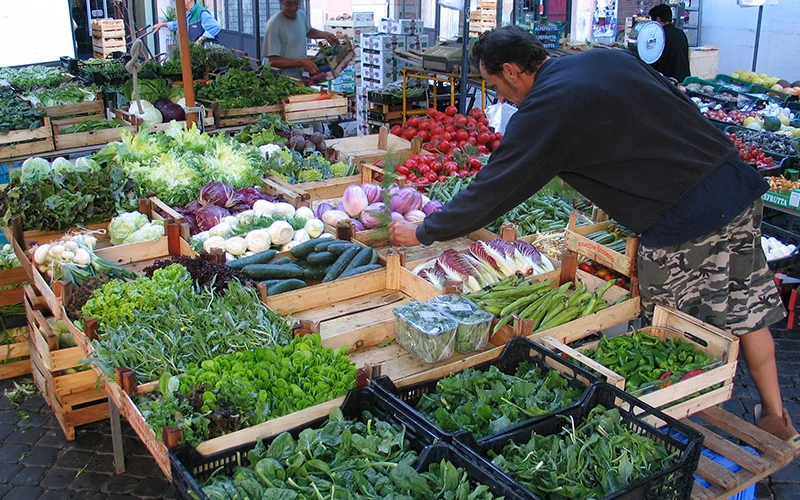 Vendor arranging vegetables at the Campo de Fiori market in Rome