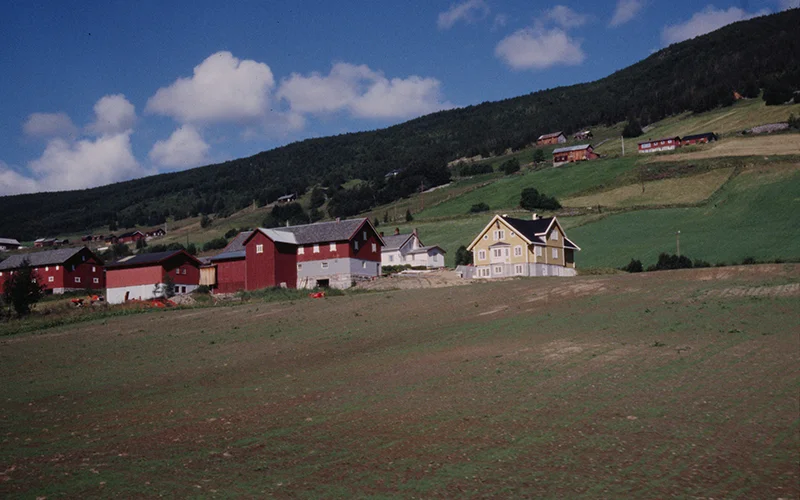 Red painted farm buildings on a green Norwegian hillside