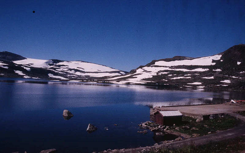 Snow beside a still mountain lake